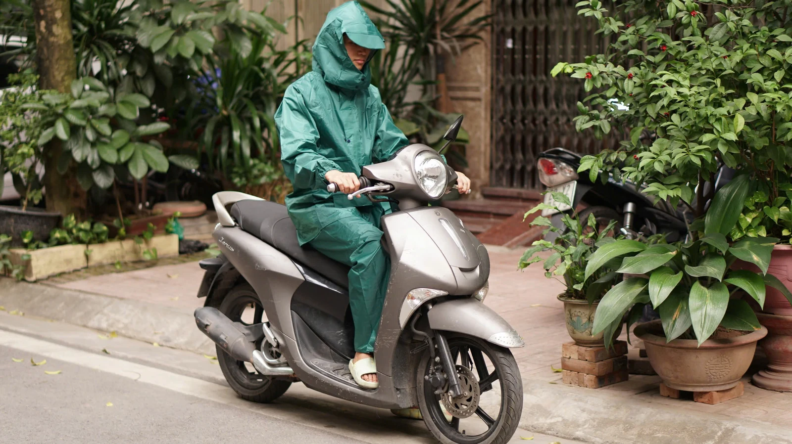Dáng bộ áo và quần mưa màu xanh lá khi người mặc ngồi trên xe