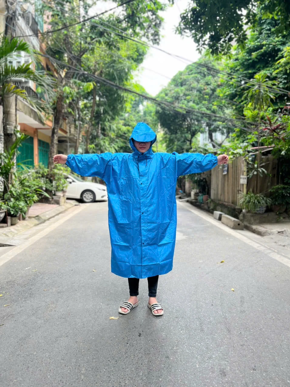 Bản áo mưa màu xanh khi đóng phần trước, có mũ và tay dài