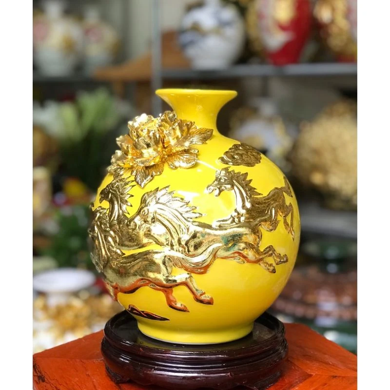 Ảnh chụp bình Mã đáo men vàng với ngựa nổi, hoa ở vai và đế gỗ