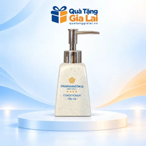 Bình dầu gội dáng thang vai xuôi men lấm tấm, vòi nhựa và chữ nhận diện trên nền Quà Tặng Gia Lai