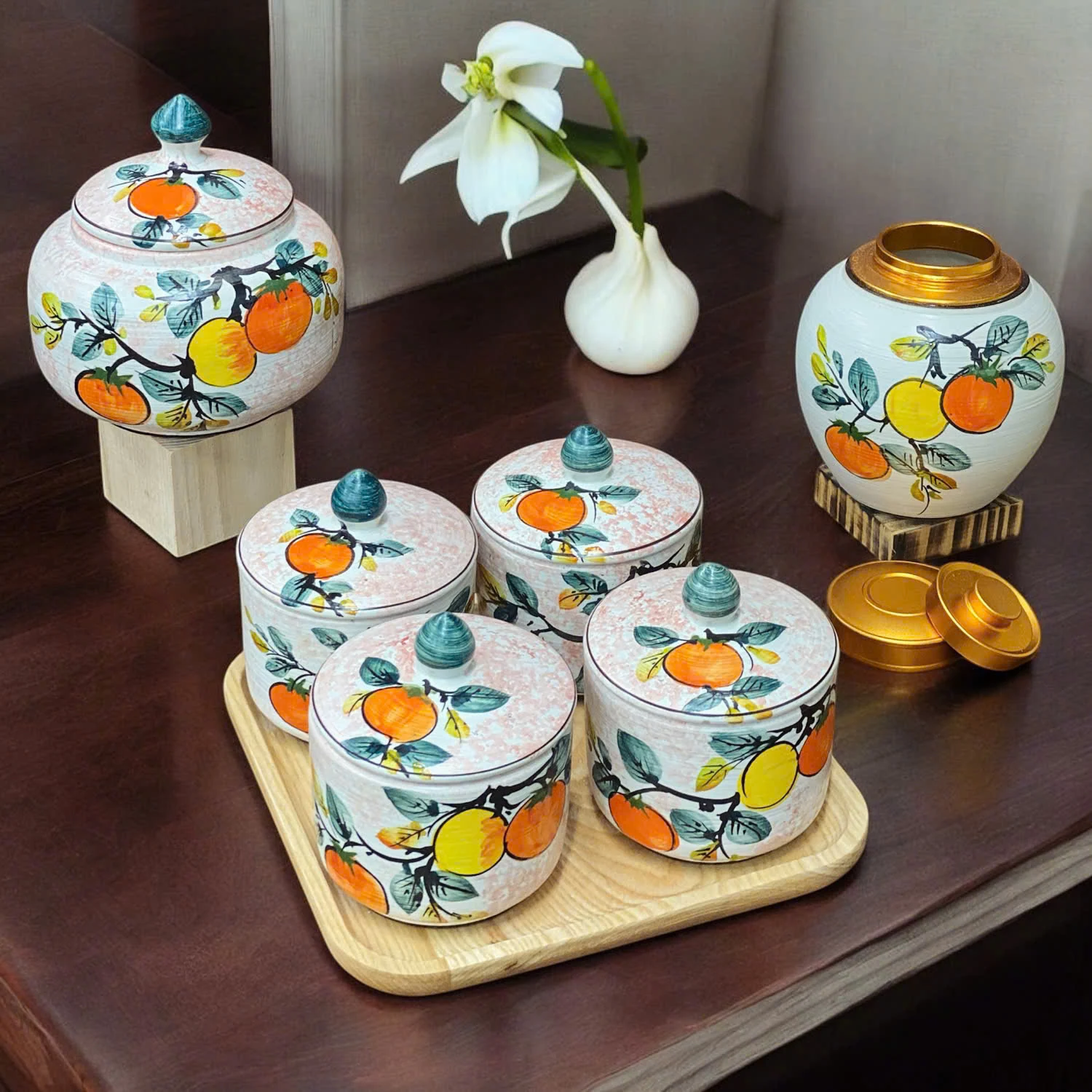 Bộ bốn hũ họa tiết quả trên khay; các hũ lớn, đế kê và bình trang trí bên cạnh không thuộc bộ.