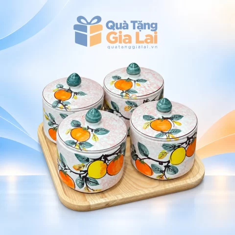 Bộ bốn hũ mứt tròn vẽ quả cam vàng núm xanh trên khay gỗ