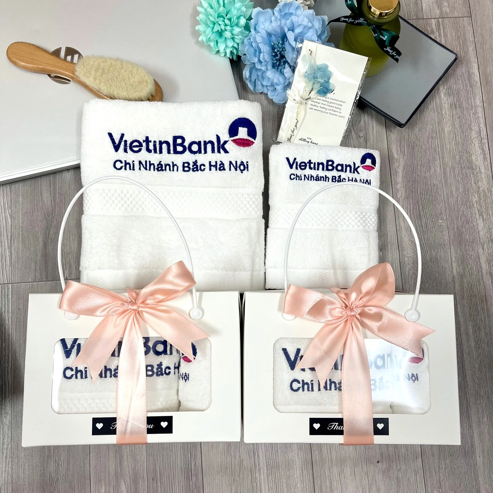 Khăn trắng thêu logo đặt phía sau hai hộp nơ đào