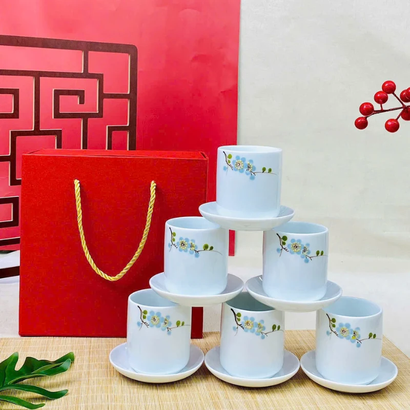 Bộ sáu cốc men trắng hoa xanh bày cạnh túi đỏ
