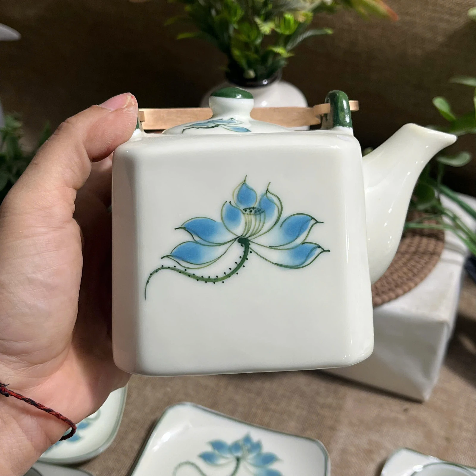 Cận mặt ấm vuông men kem vẽ hoa sen xanh lam