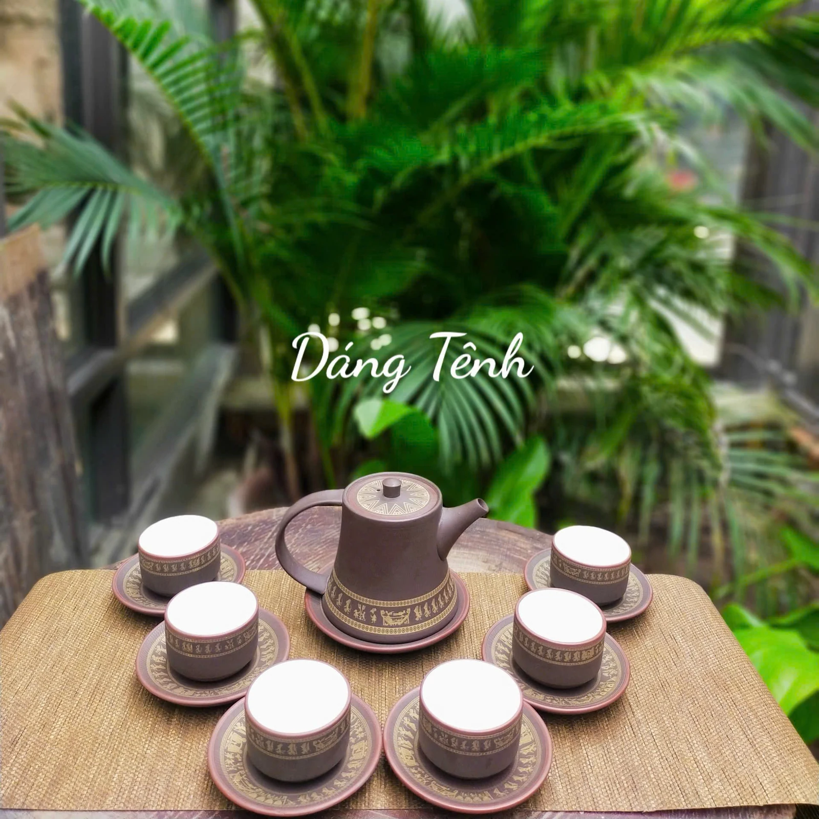 Bộ trà dáng Tênh giã gạo bày trên bàn gỗ cạnh cây xanh