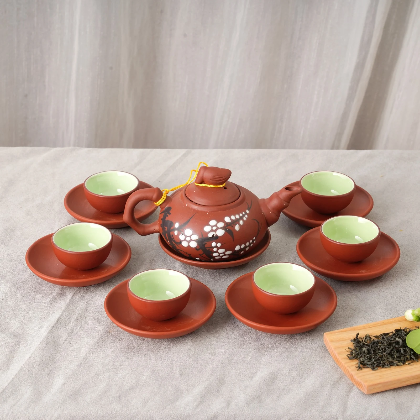 Bộ trà tử sa 12 vẽ hoa trắng trên nền vải xám, rõ quai vòng và dây nắp vàng