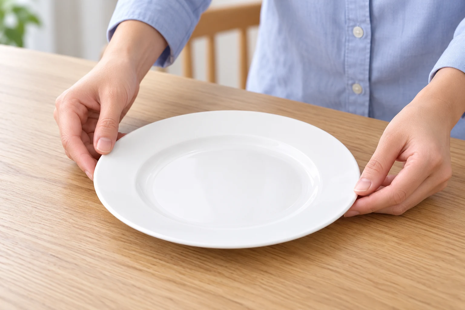 Hai tay đặt một chiếc đĩa TK-D09 men trắng lên bàn ăn