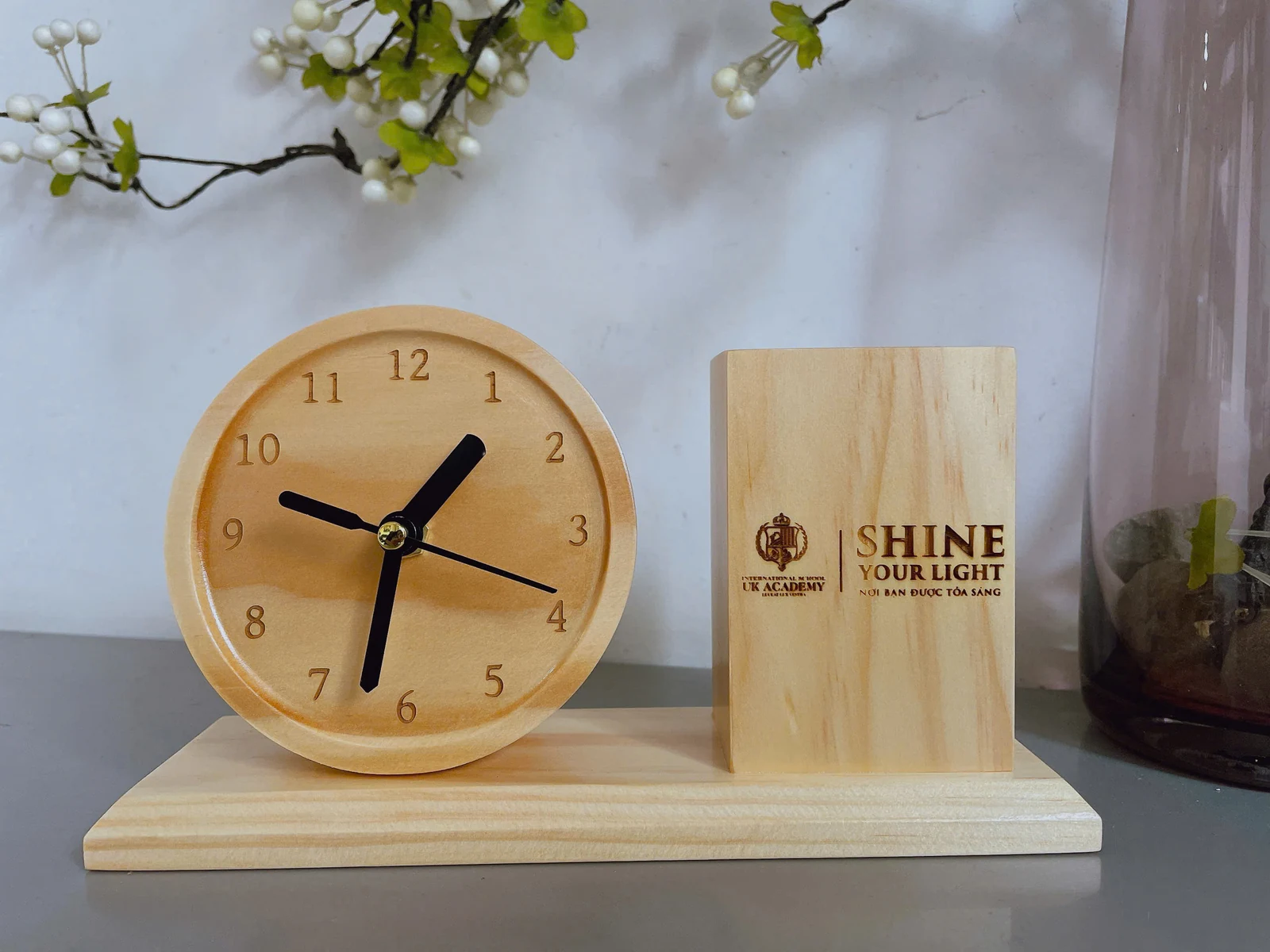 Ảnh chụp đồng hồ gỗ tròn và ống bút khắc UK Academy