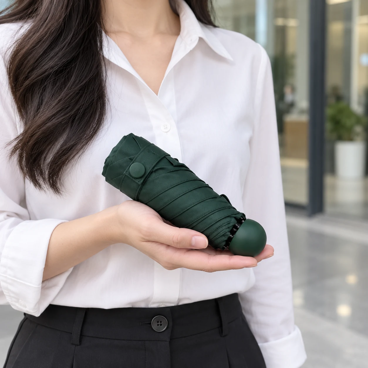 Cầm gọn dù xanh đậm gấp năm trong lòng bàn tay