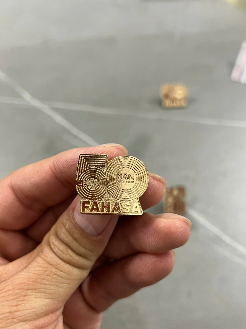 Mẫu huy hiệu cùng tông vàng, thấy đường viền và chữ trên mặt