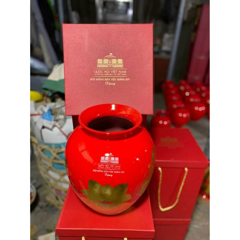 Miệng lọ H23 đỏ cam bên cạnh hộp đỏ có quai dây vàng