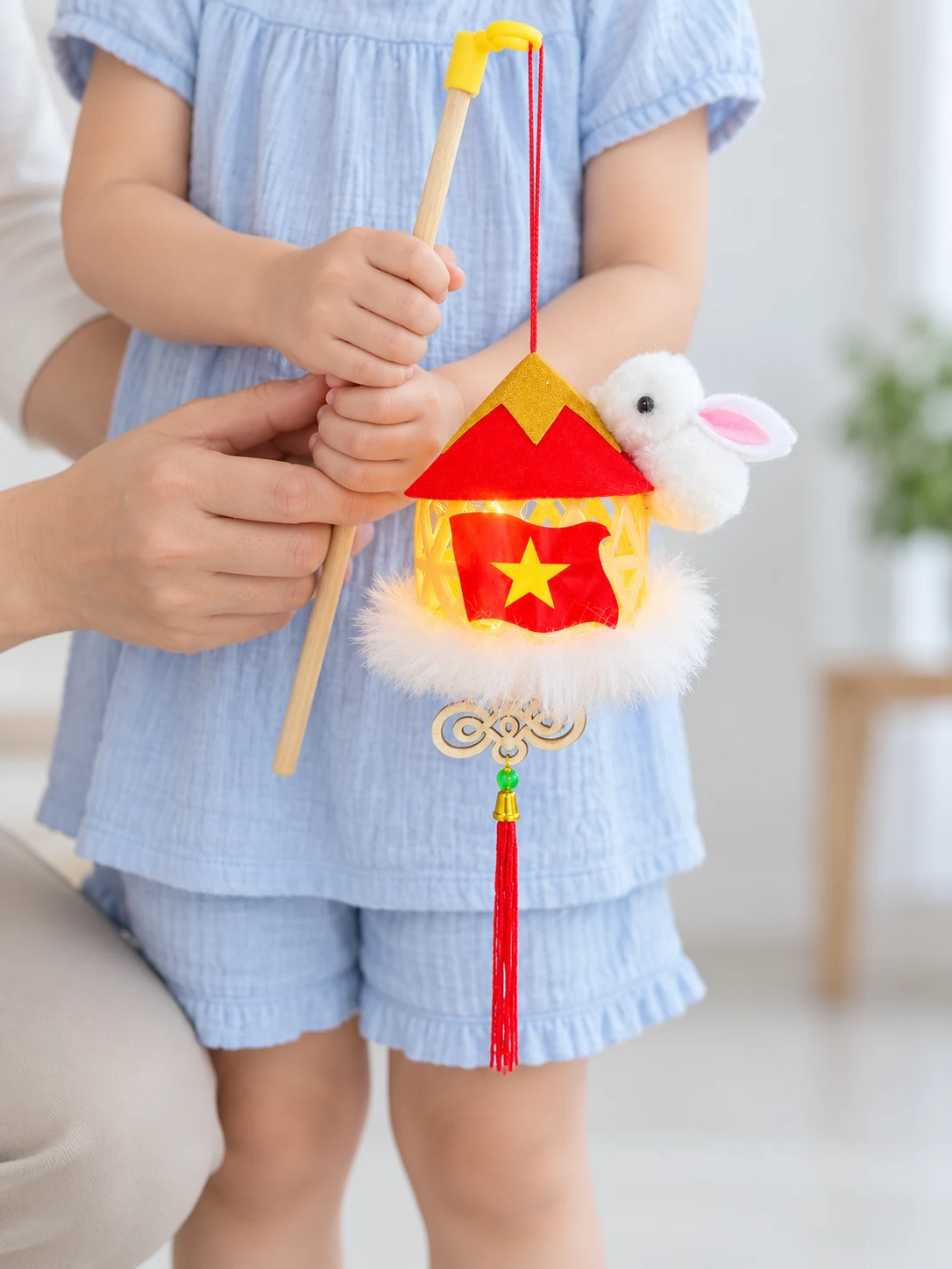 Cầm cần gỗ với mẫu thỏ bám nón đỏ sao vàng và tua đỏ