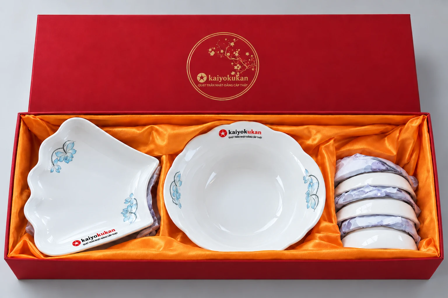 Bộ hoa xanh trong hộp đỏ lót vải vàng cam, với mẫu logo trên bát đĩa và nắp hộp