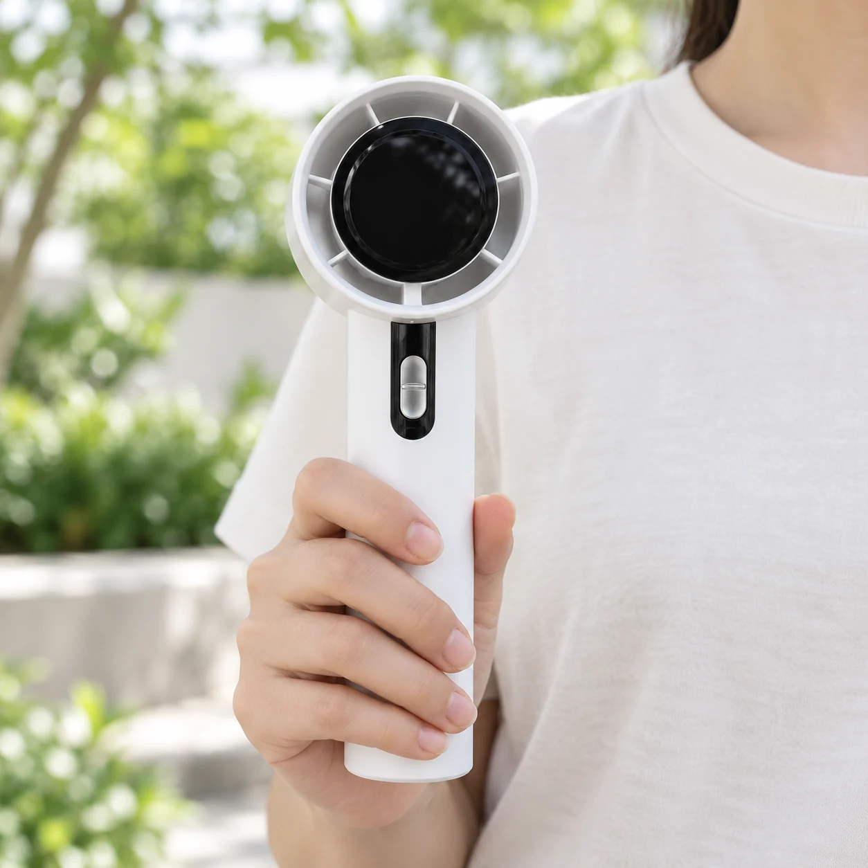 Quạt mini 03 màu trắng được cầm ở phần thân trong không gian ngoài trời