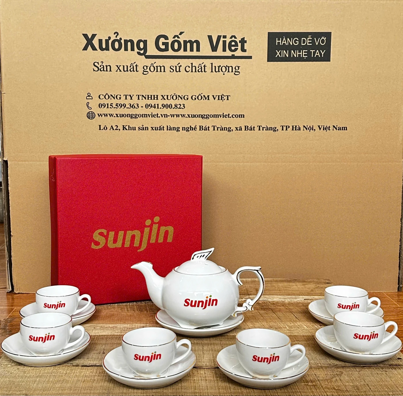 Ảnh thật bộ trà trắng in Sunjin gồm ấm, chén, đĩa và hộp đỏ đặt phía sau
