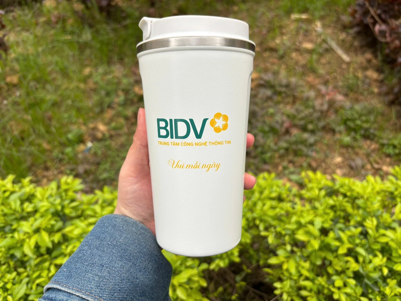 Ảnh thật cốc trắng có nắp in nhận diện BIDV được cầm trên tay