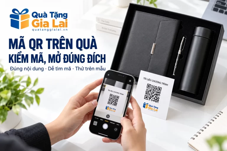 Điện thoại hướng vào thiệp QR minh họa bên bộ sổ, bình và bút