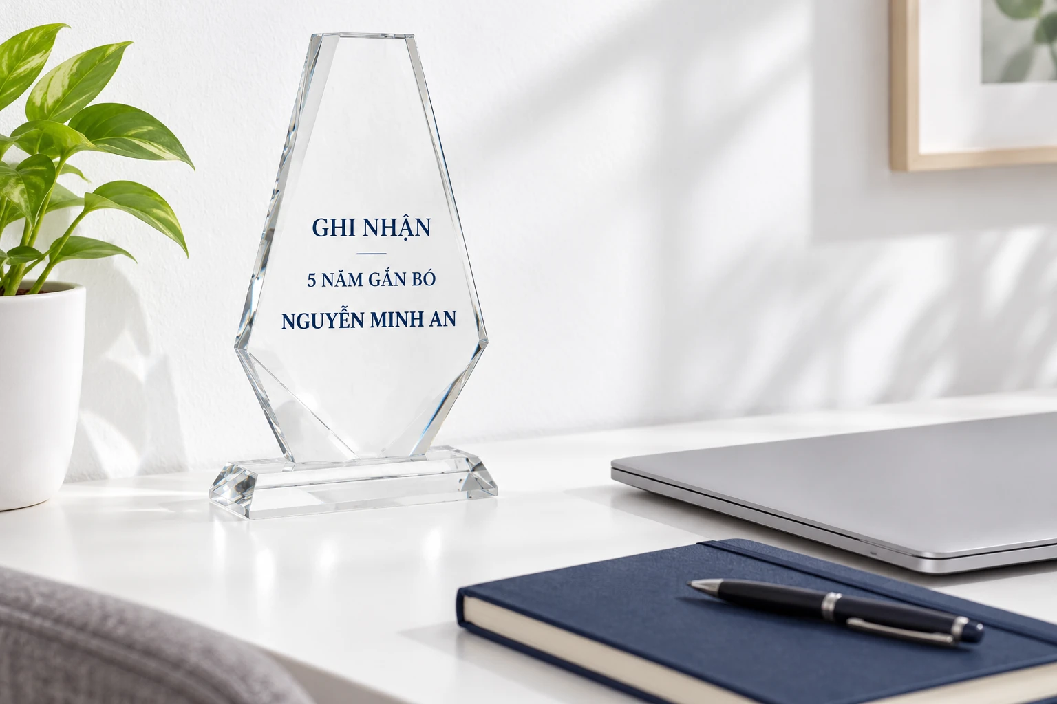 Biểu trưng tên và mốc giả định đặt ở góc bàn cạnh máy tính và sổ