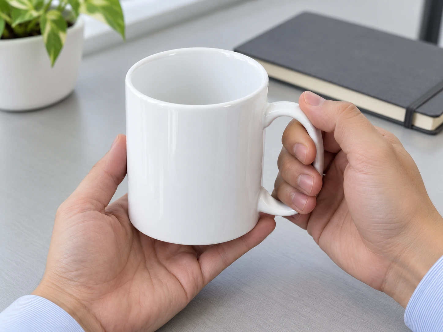 Hai tay cầm cốc trắng chưa có chữ, thấy lòng cốc và phần quai