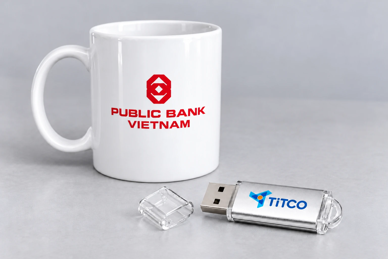 Cảnh dựng mẫu cốc trắng logo PUBLIC BANK và USB kim loại có logo TITCO