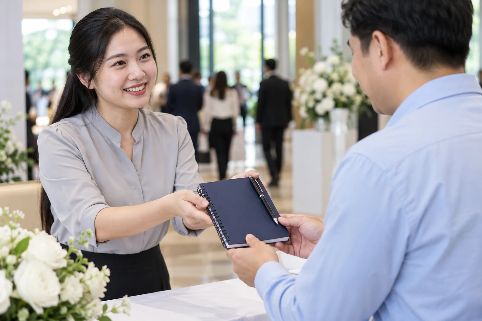Cảnh tạo nhân viên bàn đón trao sổ và bút không bọc hộp cho người dự hội nghị