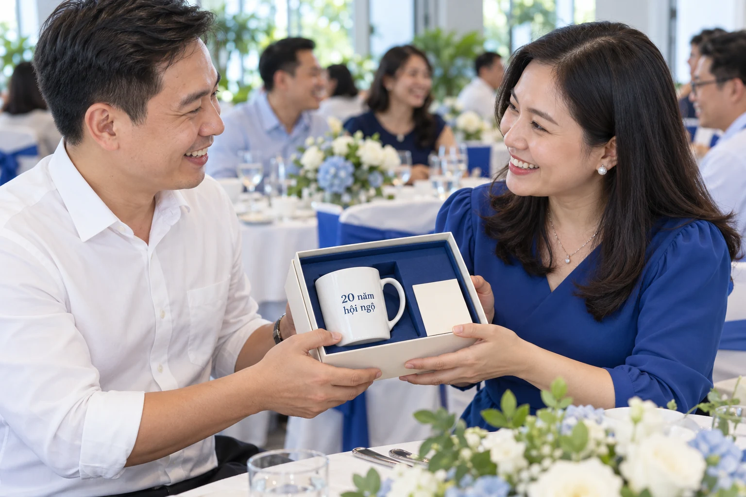 Cảnh tạo hai người bạn trao hộp cốc trắng có chữ 20 năm hội ngộ tại buổi họp lớp