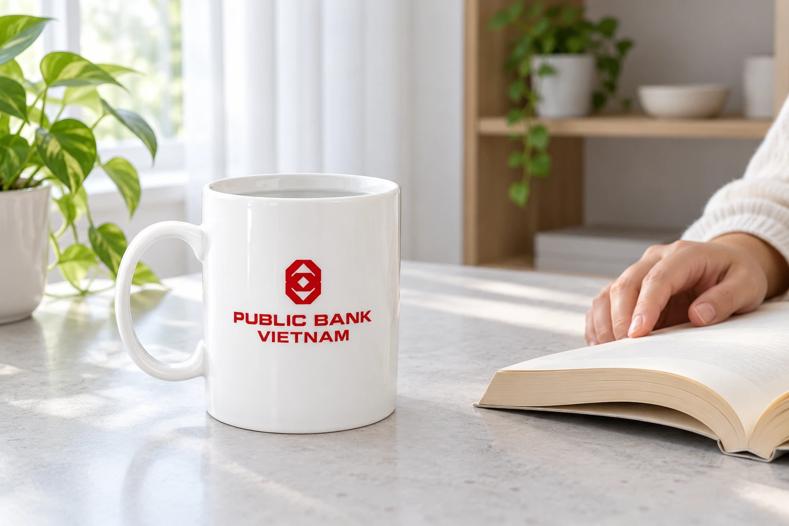 Cốc trắng có nhận diện Public Bank Vietnam đặt ở góc đọc tại nhà