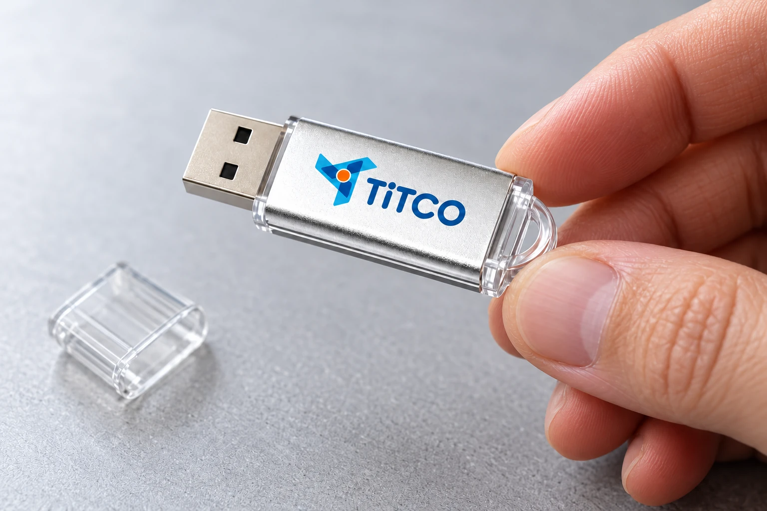 Cảnh minh họa cầm USB kim loại có logo TITCO để xem mặt chữ và góc phản sáng