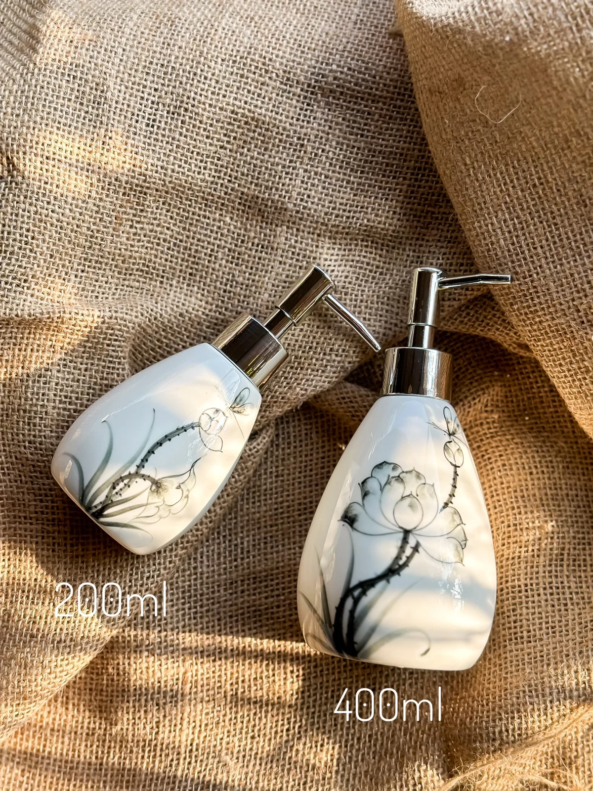 Hai cỡ bình men trắng vẽ sen: 200 ml ở bên trái và 400 ml ở bên phải