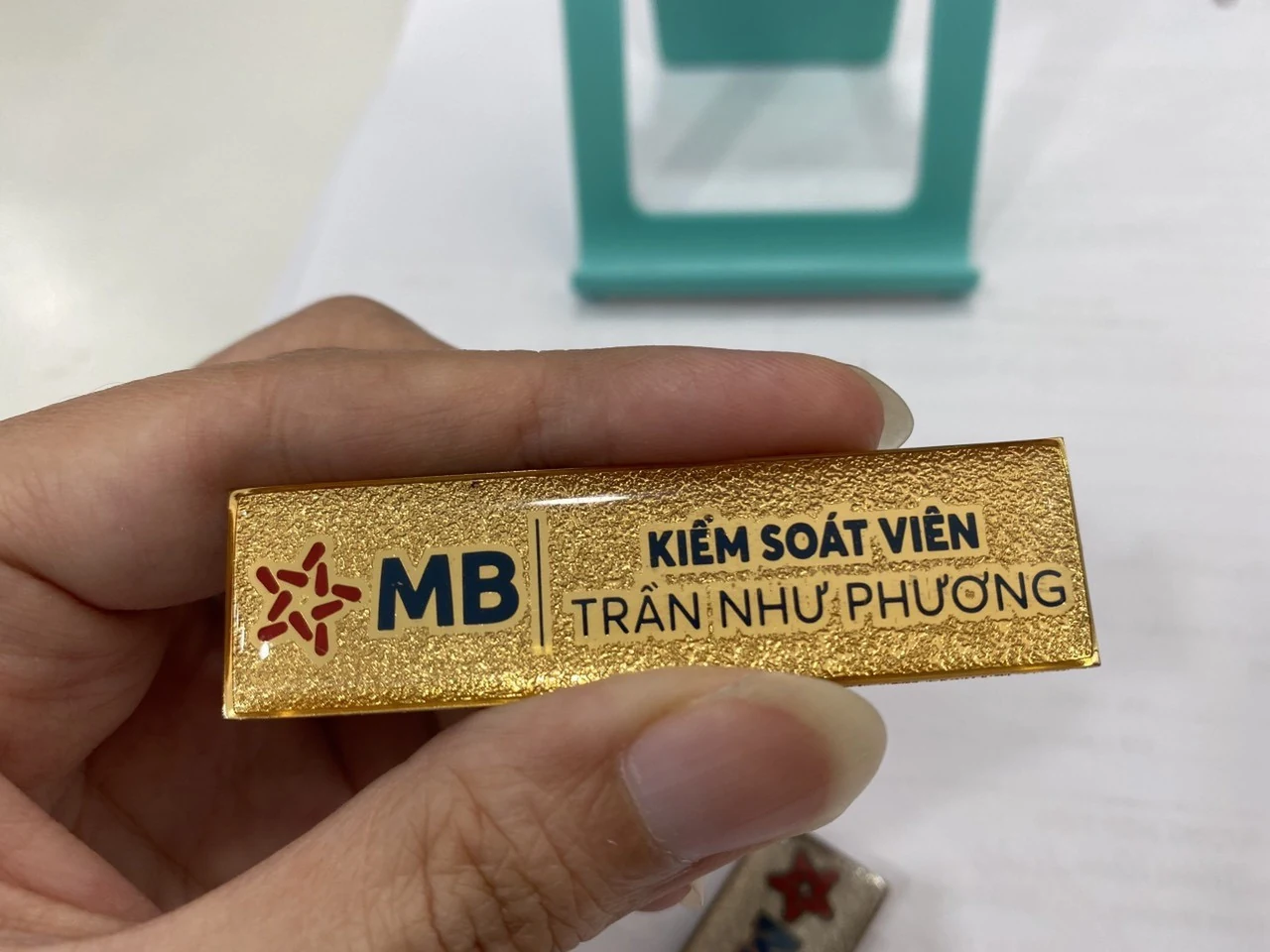 Mặt trước thẻ tên màu vàng sần với logo, chức danh và họ tên